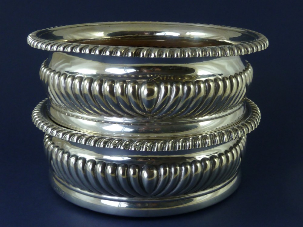 A pair of round Georgian sterling silver wine coasters with gadrooned rims, turned wooden bases, and central engraved silver bosses. View III