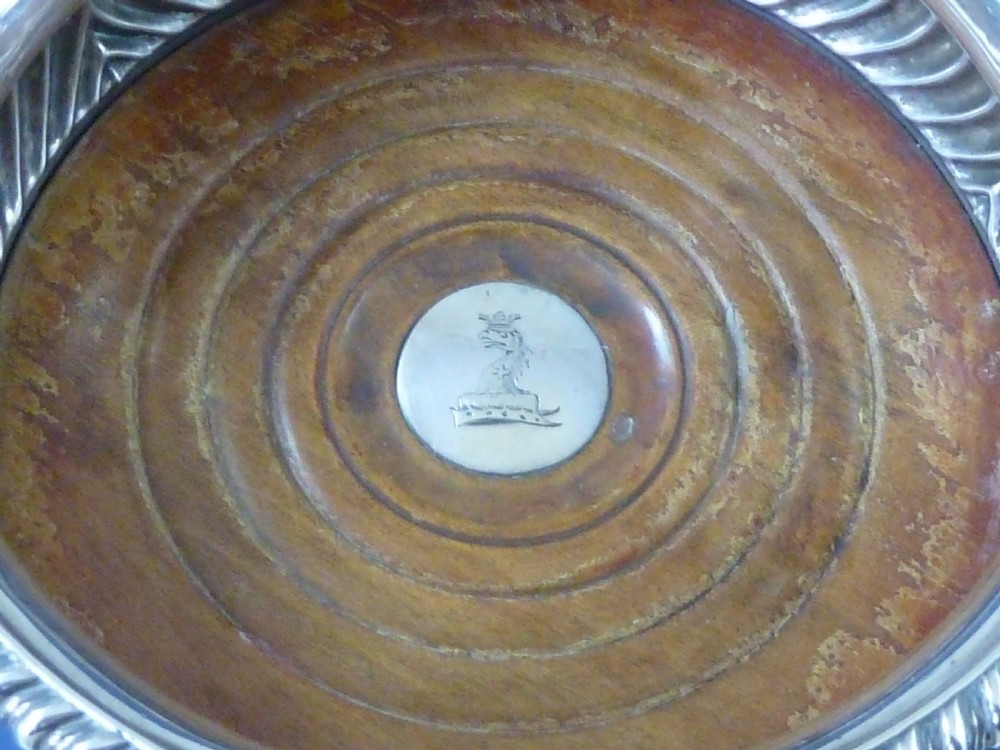 A pair of round Georgian sterling silver wine coasters with gadrooned rims, turned wooden bases, and central engraved silver bosses. View IV