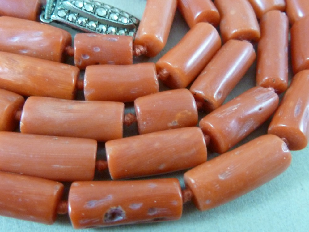 A long strand of cylindrical red coral beads wrapped multiple times around a display stand. View V