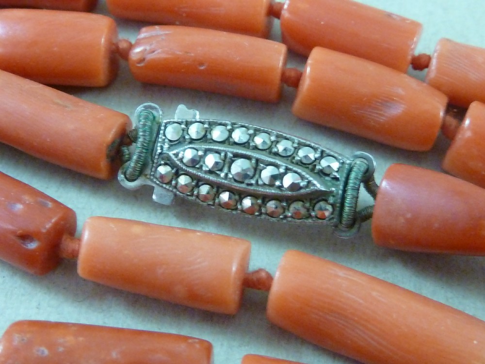 A long strand of cylindrical red coral beads wrapped multiple times around a display stand. View VI