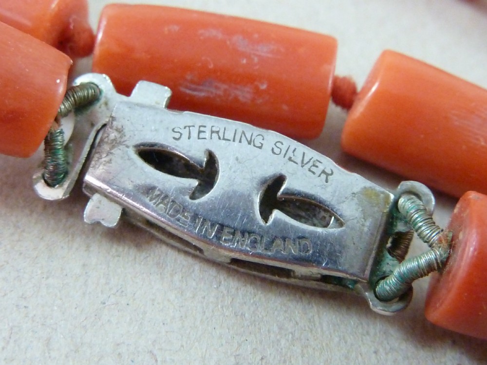 A long strand of cylindrical red coral beads wrapped multiple times around a display stand. View VII