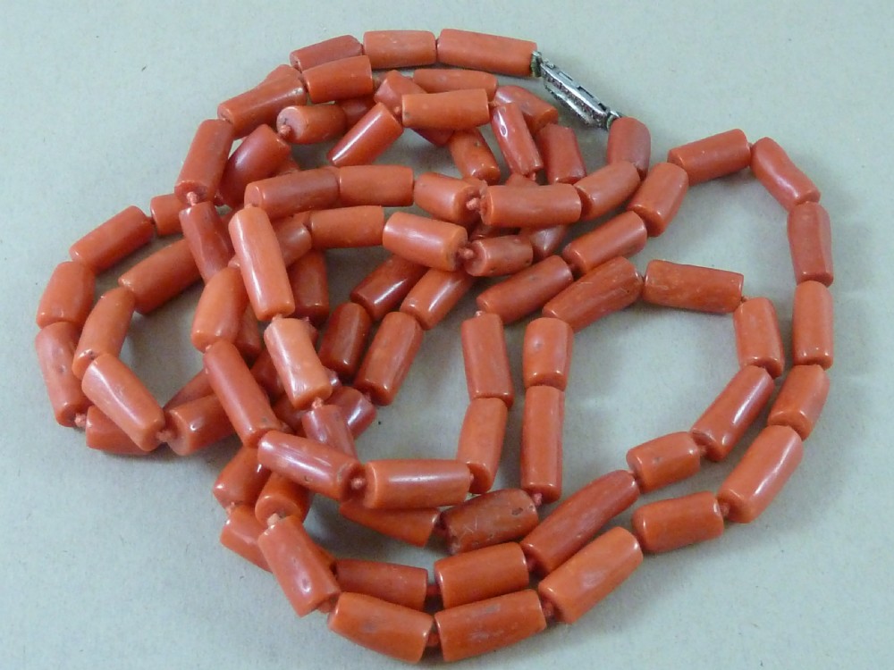 A long strand of cylindrical red coral beads wrapped multiple times around a display stand. View VIII