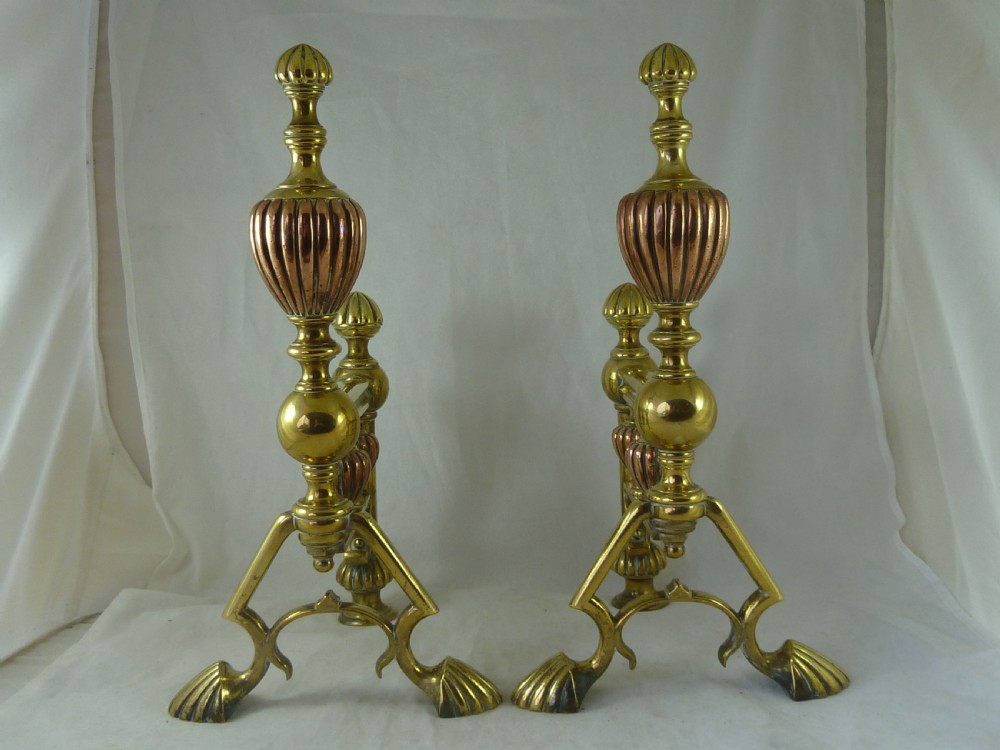 A pair of Victorian brass and copper fire dogs featuring ribbed urn-shaped finials, turned posts, and claw feet. View II