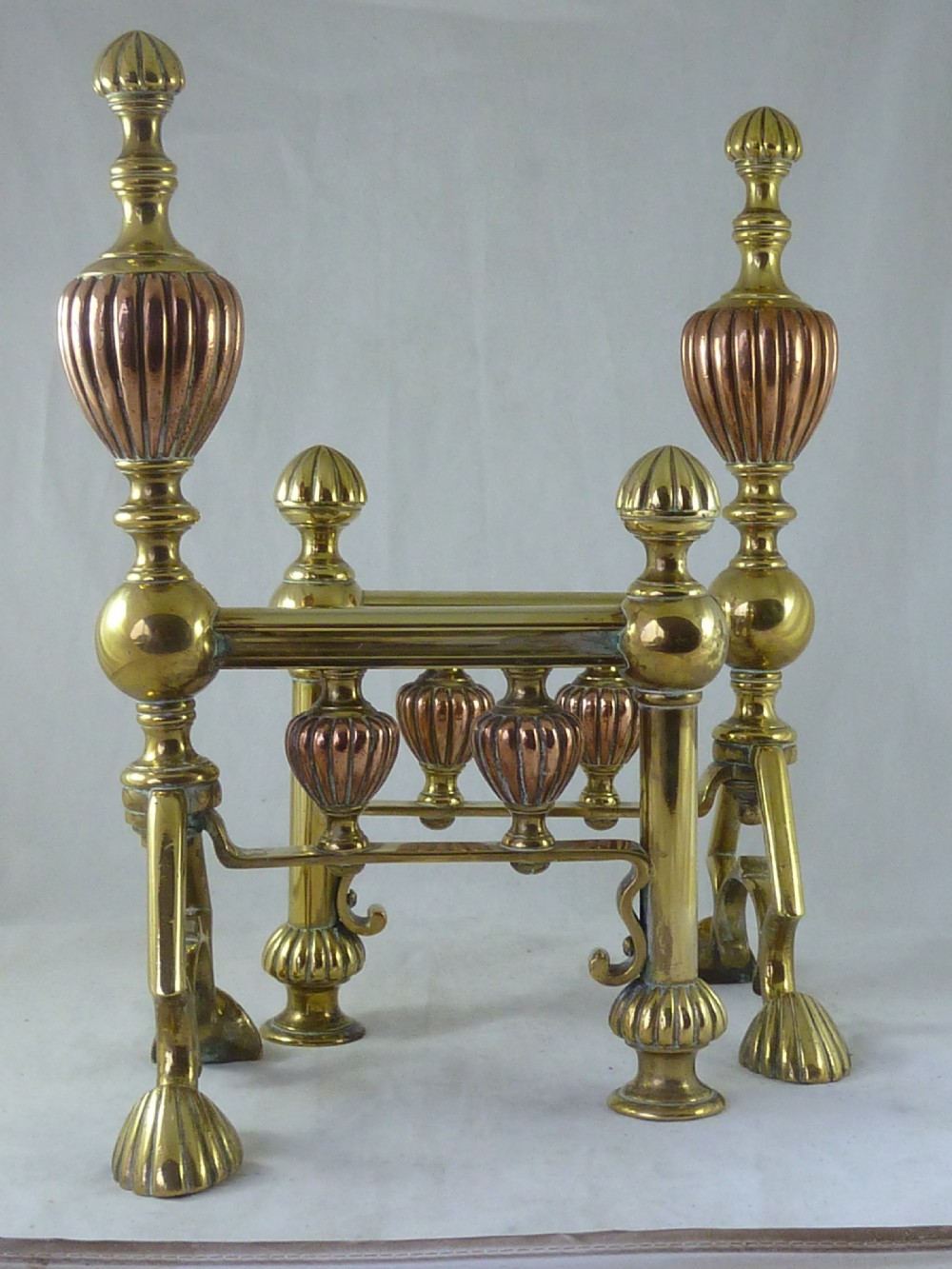 A pair of Victorian brass and copper fire dogs featuring ribbed urn-shaped finials, turned posts, and claw feet. View III