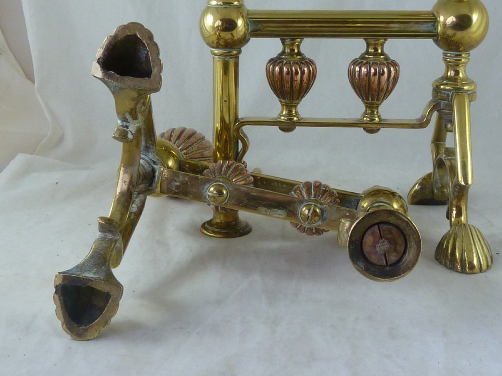 A pair of Victorian brass and copper fire dogs featuring ribbed urn-shaped finials, turned posts, and claw feet. View VI