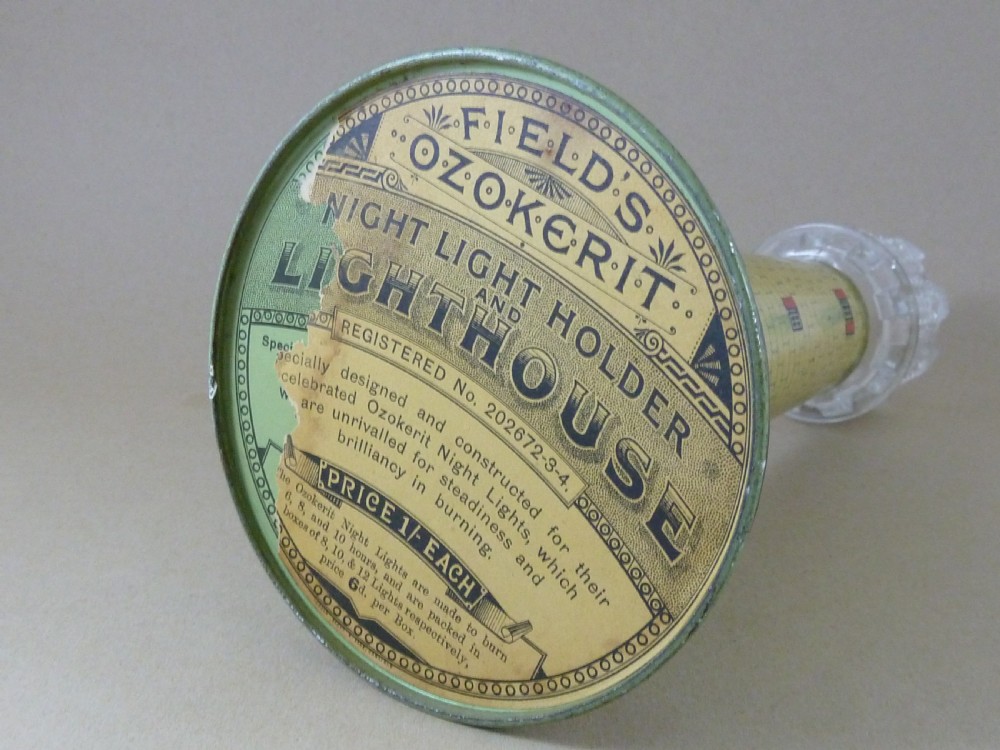 A Victorian lithographed tin candle holder shaped like a lighthouse with a clear pressed glass lantern shade. View VI