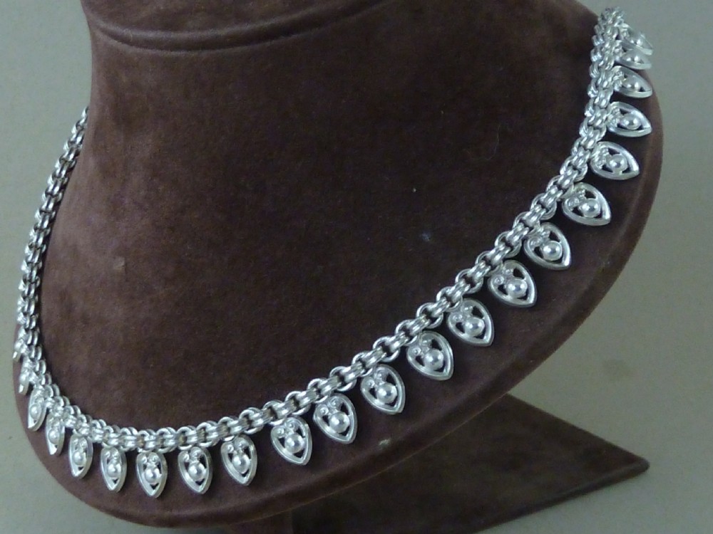 An Edwardian sterling silver collar necklace featuring a round link chain suspended with pierced heart-shaped fringe pendants. View III