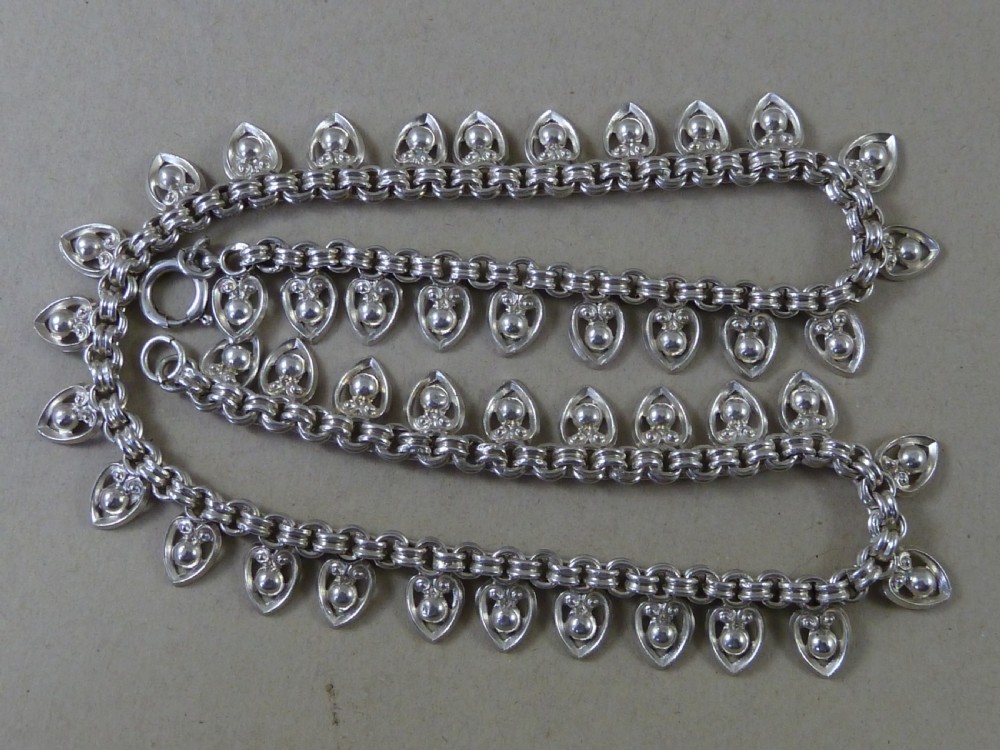 An Edwardian sterling silver collar necklace featuring a round link chain suspended with pierced heart-shaped fringe pendants. View VI