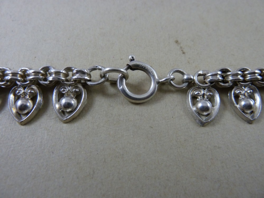 An Edwardian sterling silver collar necklace featuring a round link chain suspended with pierced heart-shaped fringe pendants. View VIII