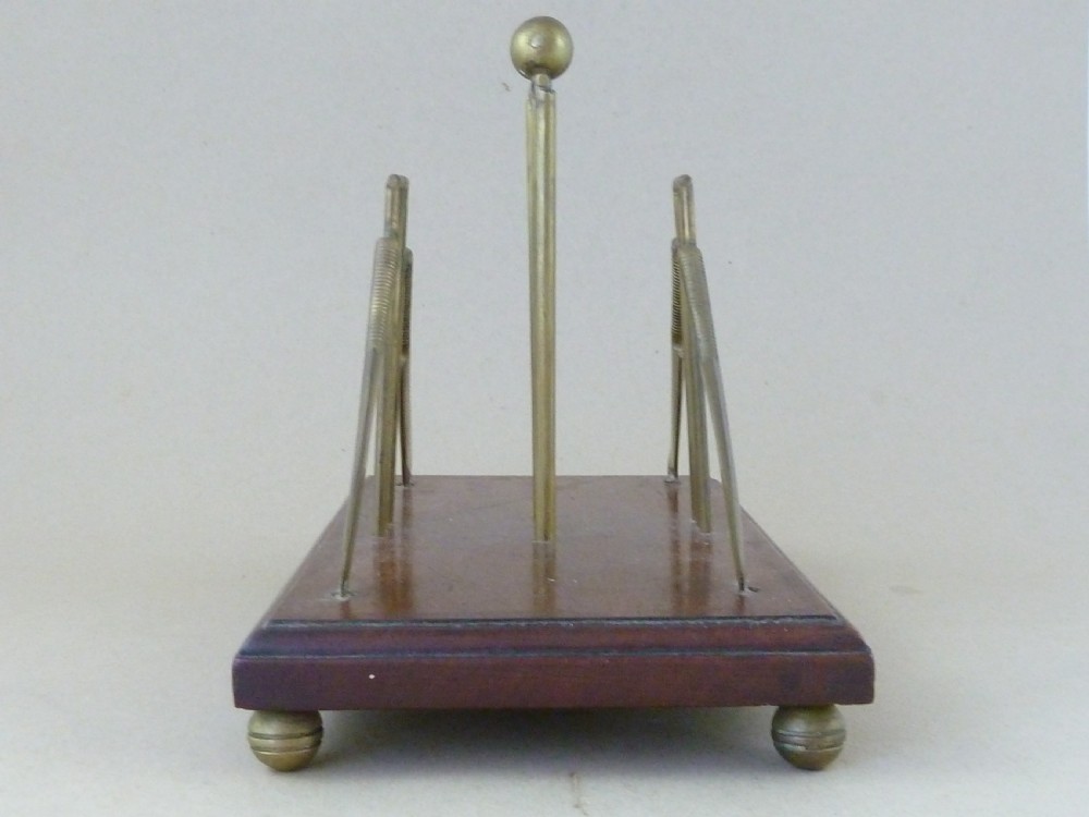An antique brass letter rack shaped as miniature cricket bats, wickets, and a ball mounted on a rectangular mahogany wooden base with small bun feet. View II
