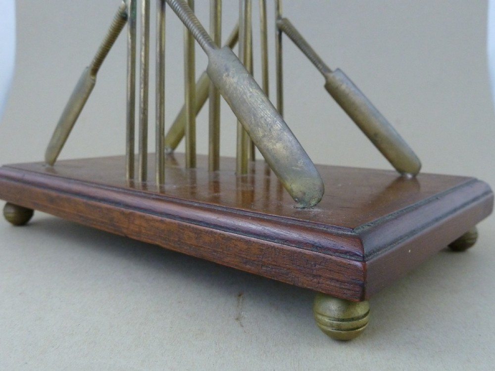 An antique brass letter rack shaped as miniature cricket bats, wickets, and a ball mounted on a rectangular mahogany wooden base with small bun feet. View VII