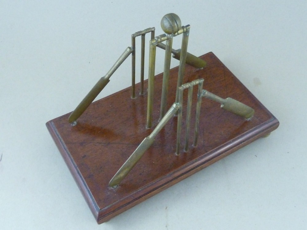 An antique brass letter rack shaped as miniature cricket bats, wickets, and a ball mounted on a rectangular mahogany wooden base with small bun feet. View VIII