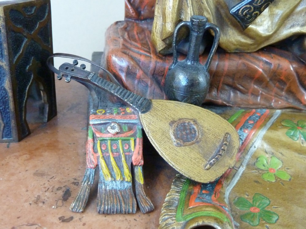 A cold-painted Vienna bronze inkstand featuring a seated figure holding a long firearm mounted on a reddish marble slab alongside twin octagonal inkwell boxes. View VII