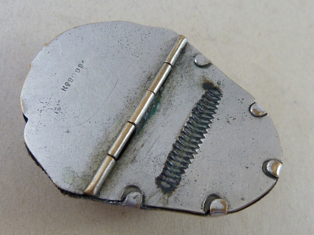 A nickel-plated metal vesta case cast in the high-relief shape of a mans face wearing a monocle. View IV