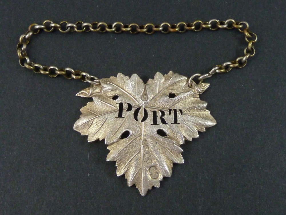 A Victorian sterling silver decanter label shaped as a vine leaf, pierced with the word PORT and attached to a metal suspension chain. View IV