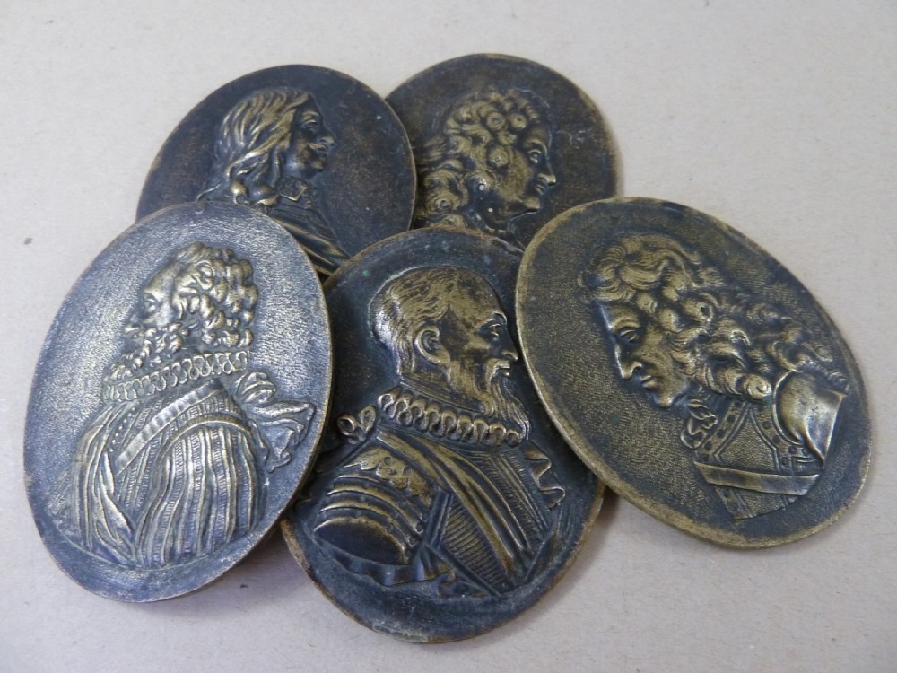 A set of five dark bronze oval portrait medallions depicting historical figures, alongside decorative cast brass frames with bow motifs. View VIII