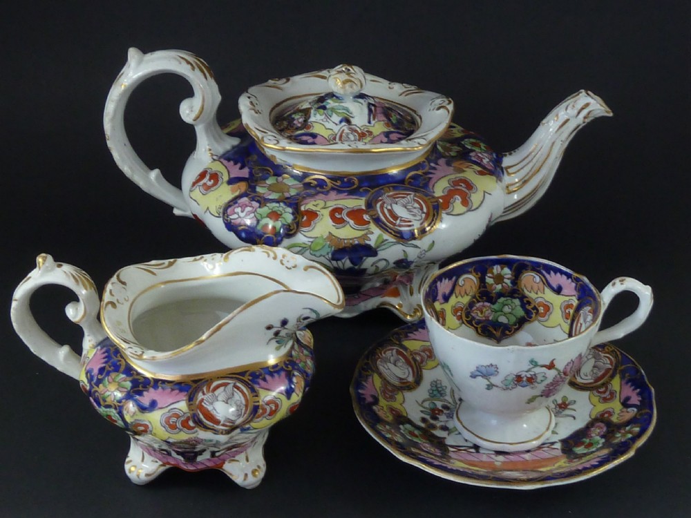 A Masons ironstone tea set featuring a teapot, milk jug, and teacup with saucer in cobalt blue, pink, and yellow enamelling with gilded details.