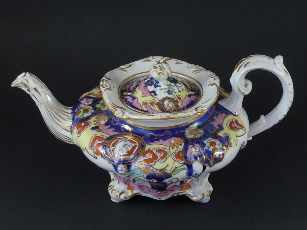 A Masons ironstone tea set featuring a teapot, milk jug, and teacup with saucer in cobalt blue, pink, and yellow enamelling with gilded details. View IV