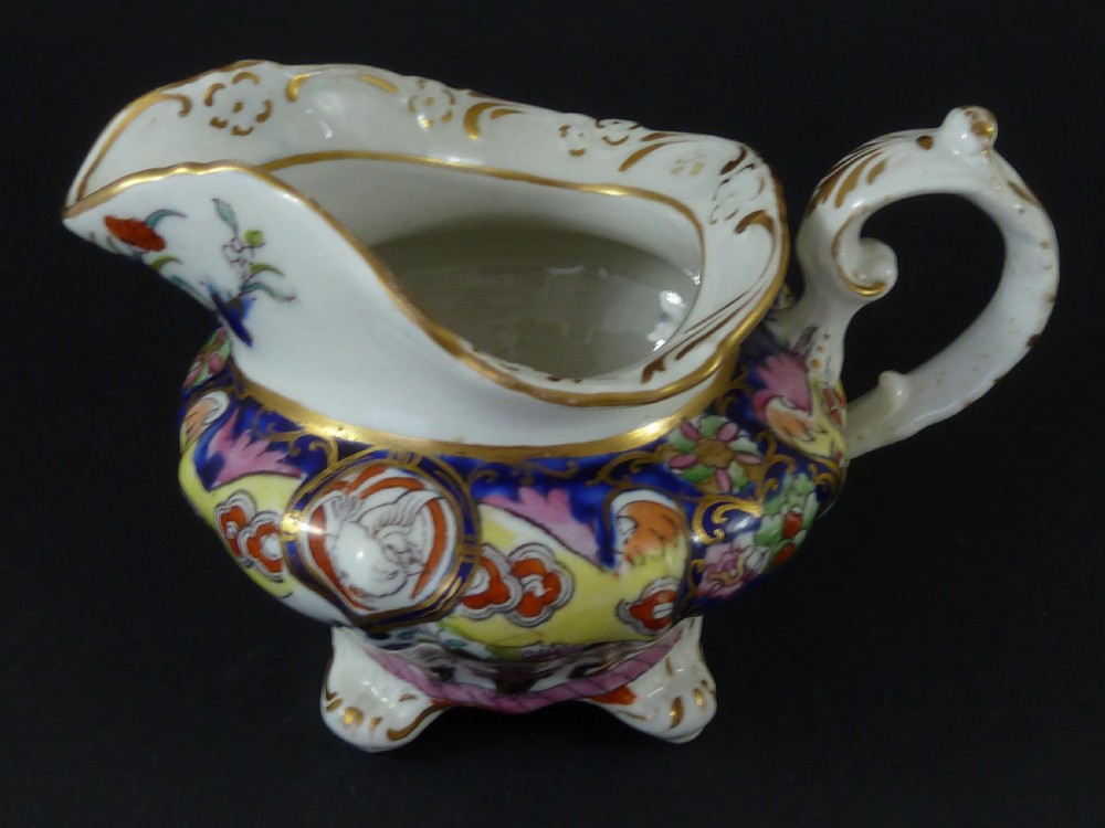 A Masons ironstone tea set featuring a teapot, milk jug, and teacup with saucer in cobalt blue, pink, and yellow enamelling with gilded details. View V