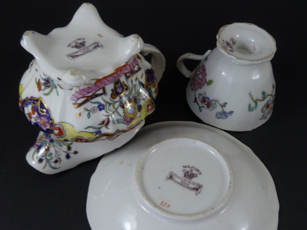 A Masons ironstone tea set featuring a teapot, milk jug, and teacup with saucer in cobalt blue, pink, and yellow enamelling with gilded details. View IX