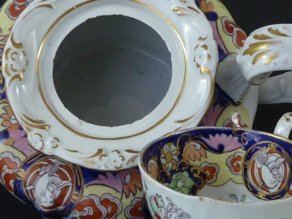 A Masons ironstone tea set featuring a teapot, milk jug, and teacup with saucer in cobalt blue, pink, and yellow enamelling with gilded details. View X
