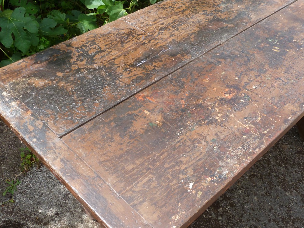 A rustic painted pine tavern table featuring an X-frame trestle base, an iron stretcher rod, and a weathered two-plank top with cleated ends. View VII