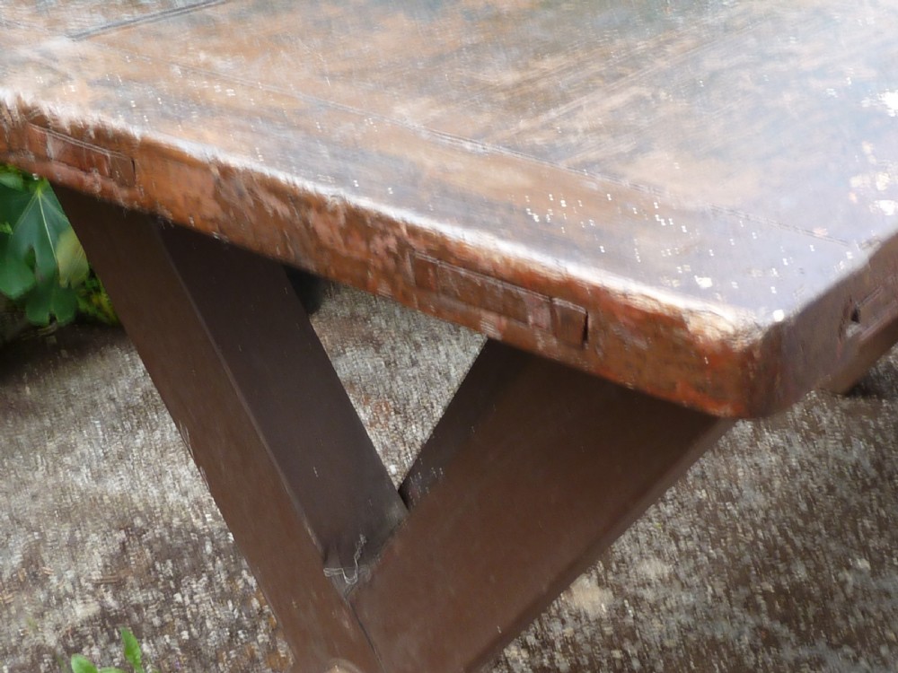 A rustic painted pine tavern table featuring an X-frame trestle base, an iron stretcher rod, and a weathered two-plank top with cleated ends. View X