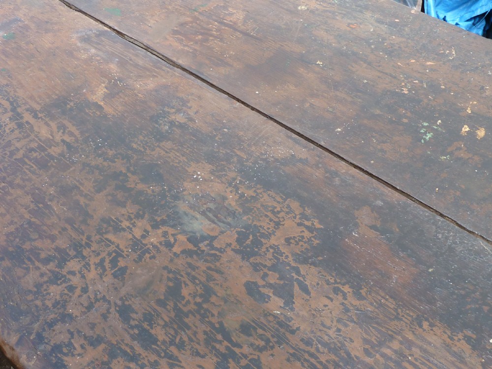 A rustic painted pine tavern table featuring an X-frame trestle base, an iron stretcher rod, and a weathered two-plank top with cleated ends. View XII