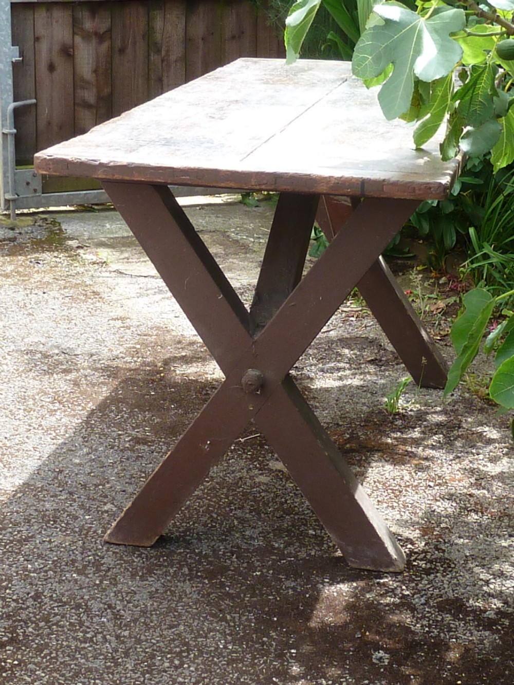 A rustic painted pine tavern table featuring an X-frame trestle base, an iron stretcher rod, and a weathered two-plank top with cleated ends. View XVII