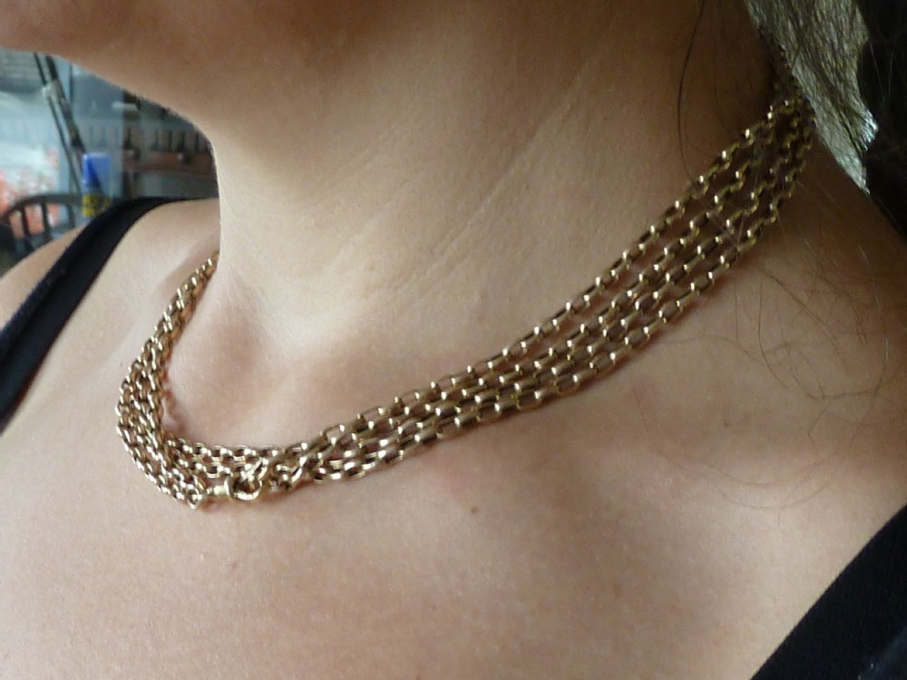 A long 14ct yellow gold Victorian guard chain featuring interlocking oval links and a dog clip clasp, laid flat against a neutral surface. View VII