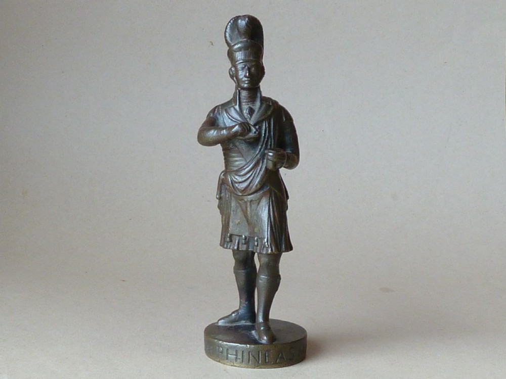 A dark bronze figure depicting a Scottish Highlander in military uniform standing on a circular base inscribed with text. View VI