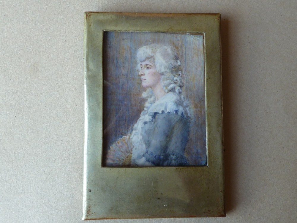 A profile portrait miniature painting of a lady in an eighteenth-century style powdered wig and ruffled blue dress, signed and dated 1914. View II