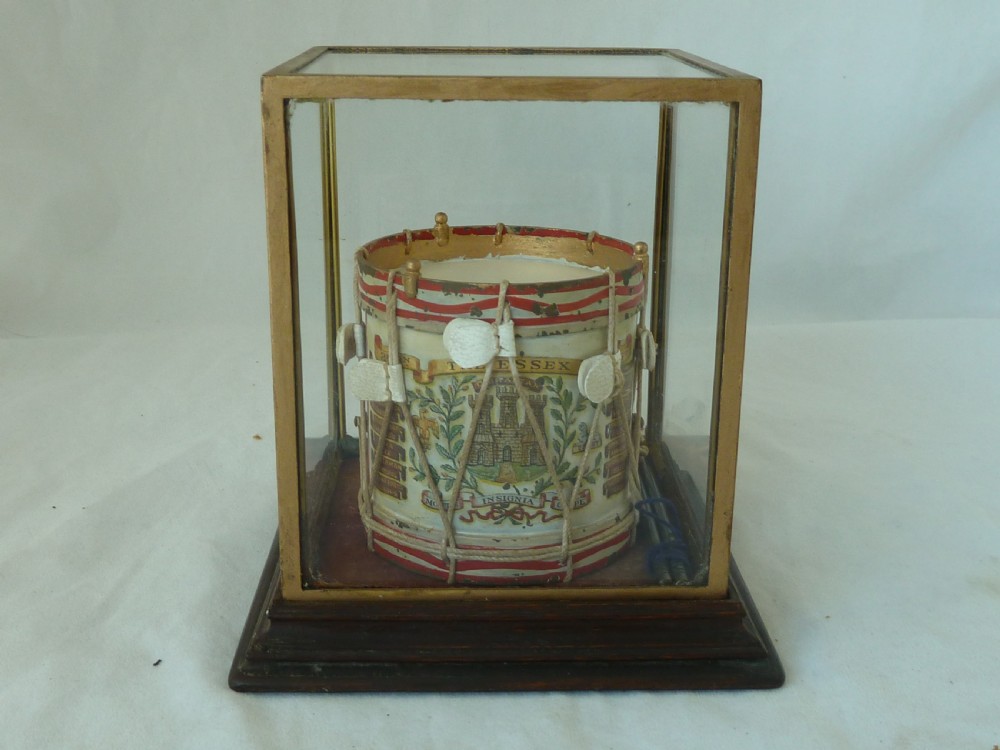 A miniature painted regimental snare drum with rope tensioning enclosed within a brass-bound glass display case on a dark timber base.
