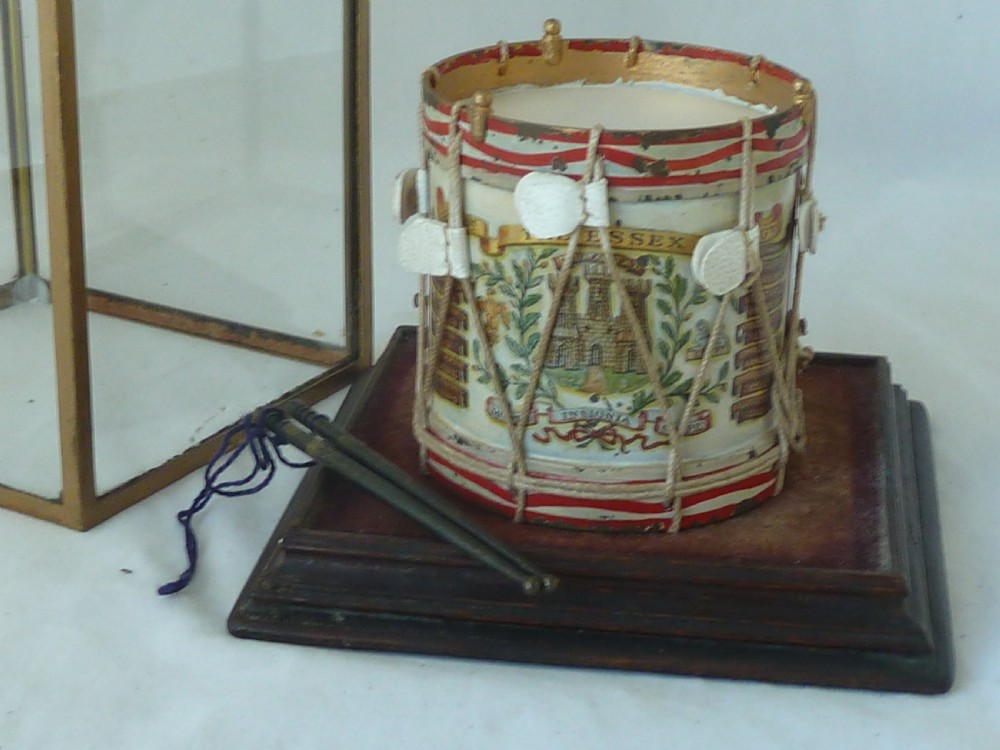 A miniature painted regimental snare drum with rope tensioning enclosed within a brass-bound glass display case on a dark timber base. View III