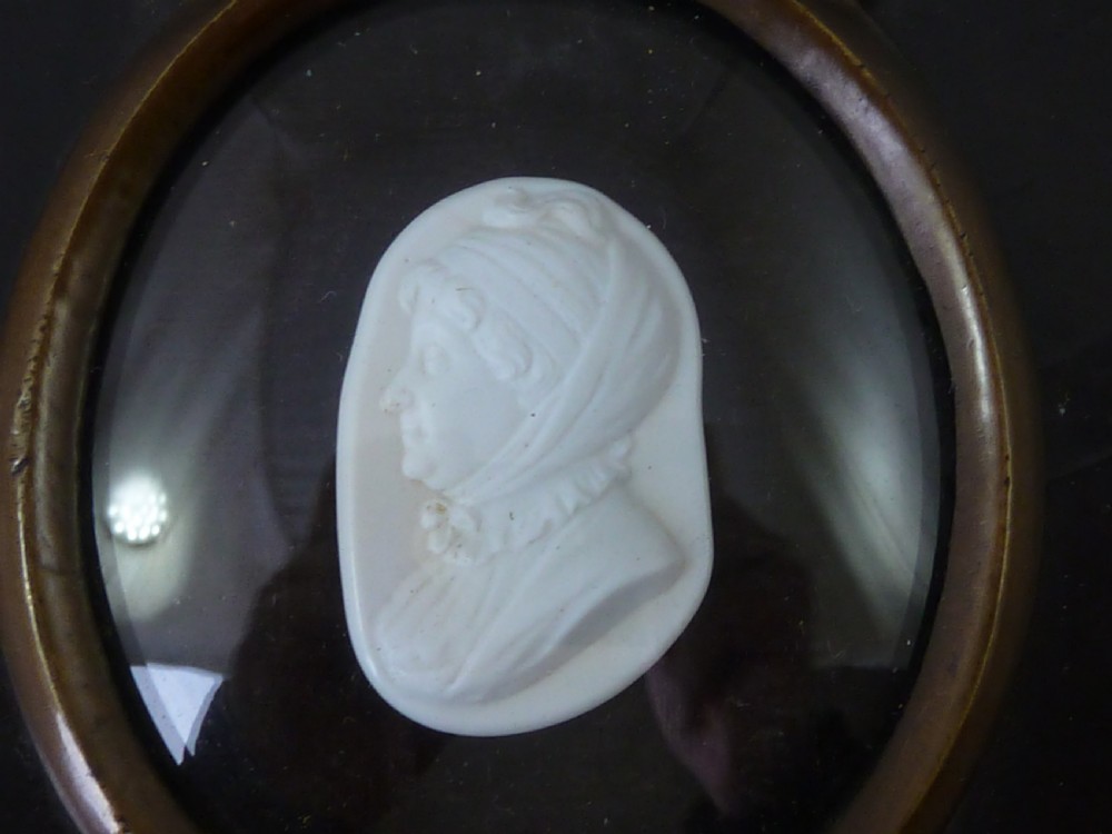 A Georgian oval white glass paste profile bust miniature mounted in a brass bezel on a rectangular black ebonised wooden plaque with a brass acorn hanger. View III