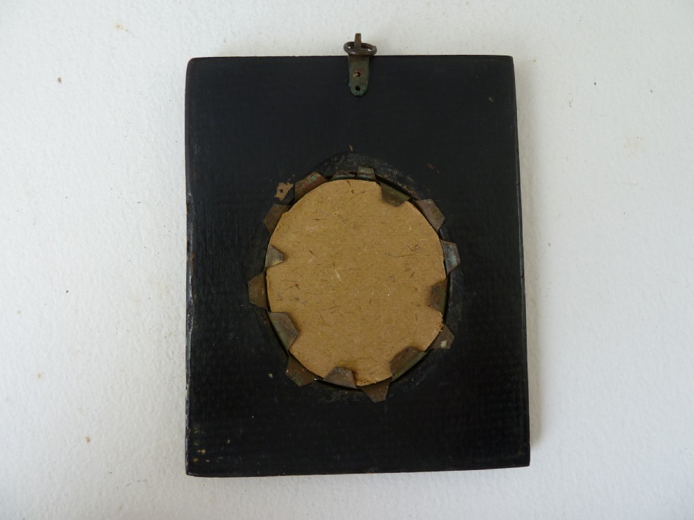 A Georgian oval white glass paste profile bust miniature mounted in a brass bezel on a rectangular black ebonised wooden plaque with a brass acorn hanger. View IV