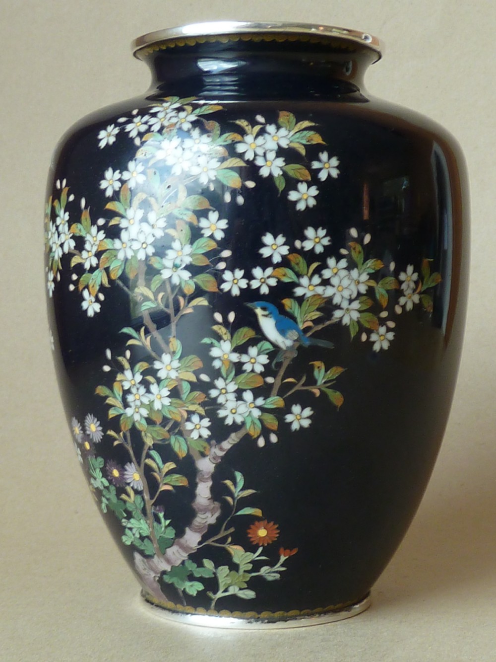 A black Japanese cloisonne enamel vase decorated with silver wire depicting white blossoms, foliage, and birds, finished with silver rim and foot rim. View IV