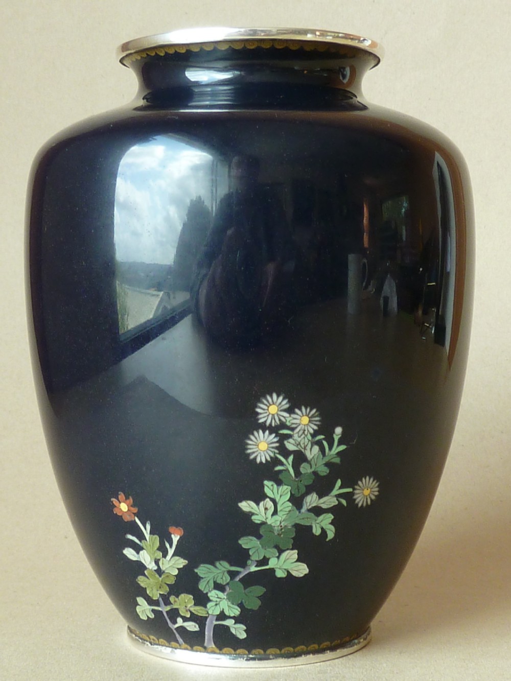 A black Japanese cloisonne enamel vase decorated with silver wire depicting white blossoms, foliage, and birds, finished with silver rim and foot rim. View V