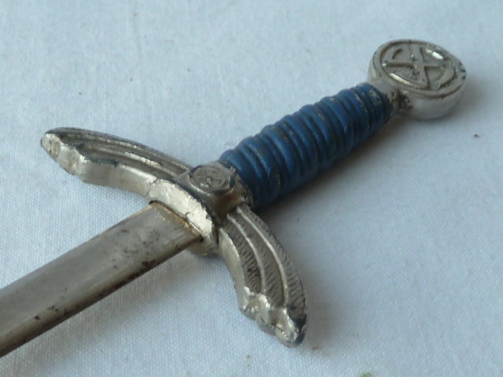 A miniature dagger letter opener featuring a tapered steel blade, down-swept crossguard, ribbed blue handle, and circular pommel. View IV
