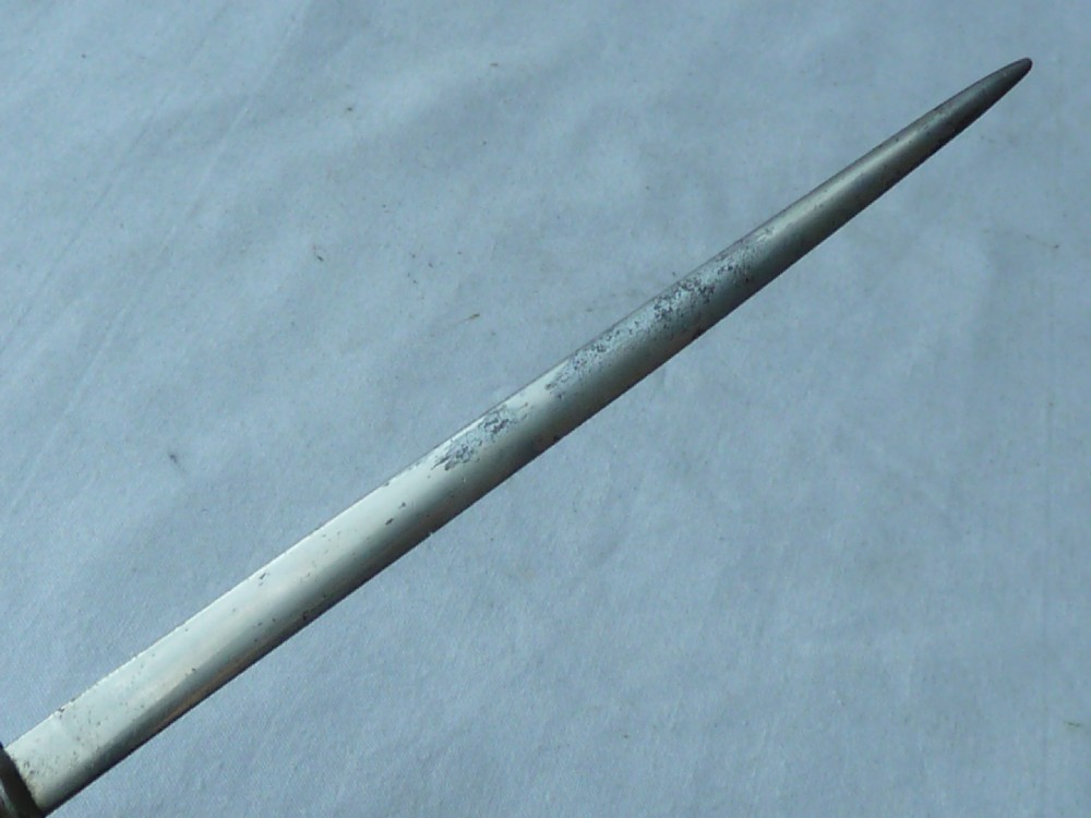 A miniature dagger letter opener featuring a tapered steel blade, down-swept crossguard, ribbed blue handle, and circular pommel. View V