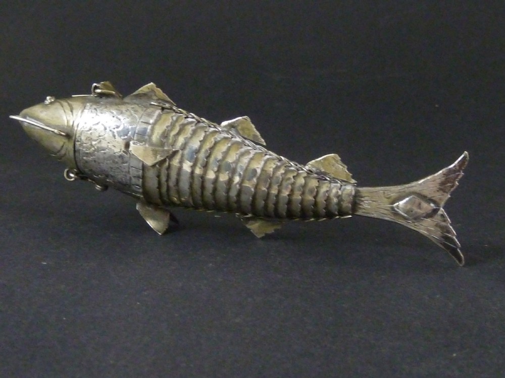 An articulated silver spice box crafted in the form of a detailed fish with overlapping scales and fins. View II