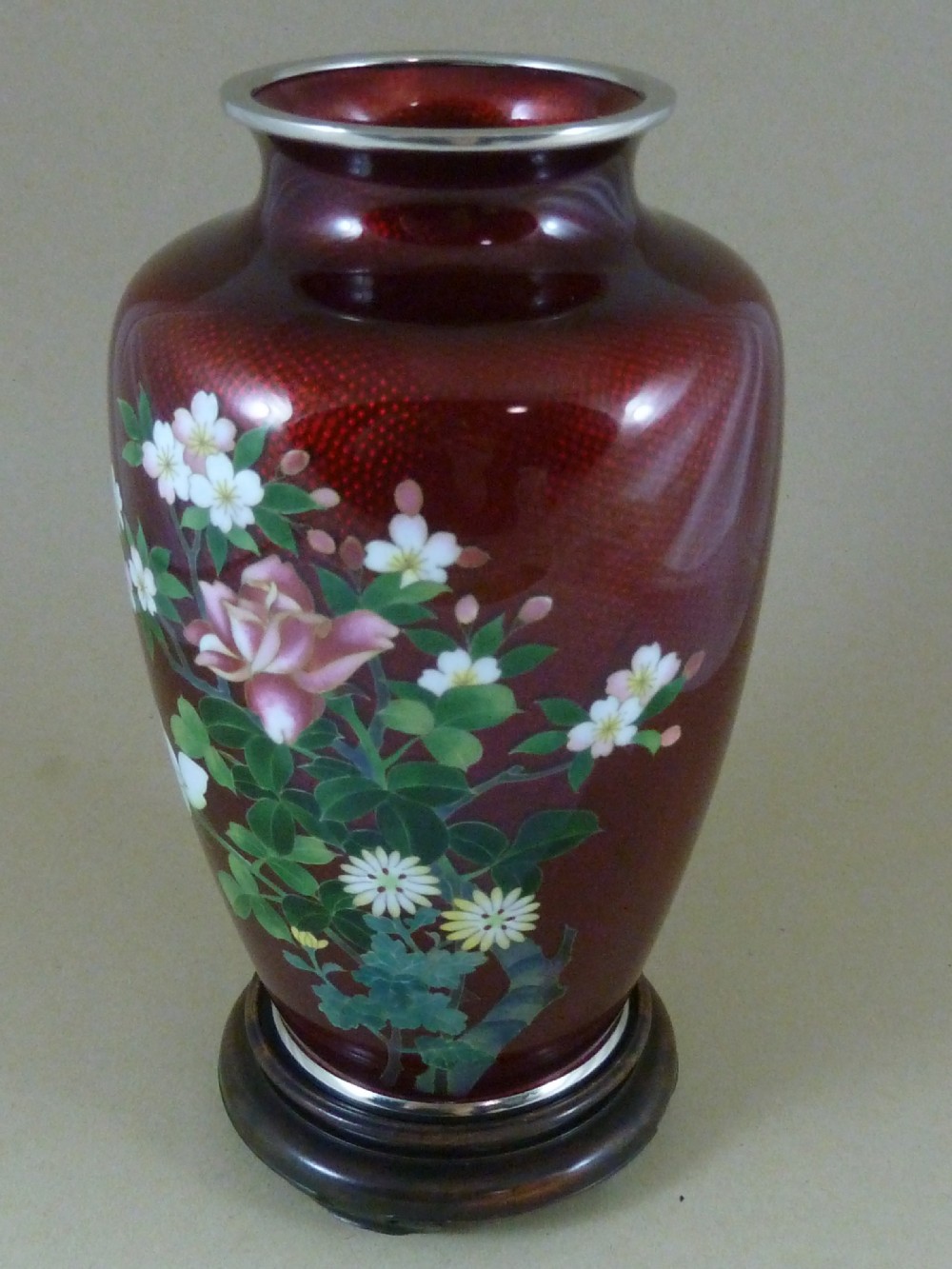 A red Japanese ginbari enamel vase decorated with floral silver wire motifs set upon a dark carved wooden base. View IV
