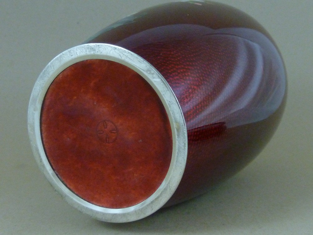 A red Japanese ginbari enamel vase decorated with floral silver wire motifs set upon a dark carved wooden base. View VI