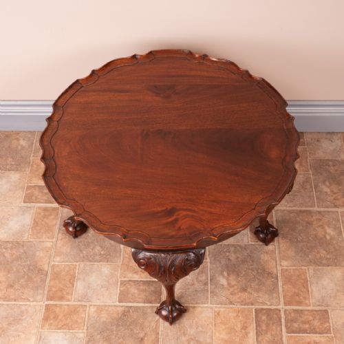 fig 1. A circular mahogany coffee table featuring a scalloped piecrust rim, carved acanthus foliage on cabriole legs, and ball-and-claw feet.