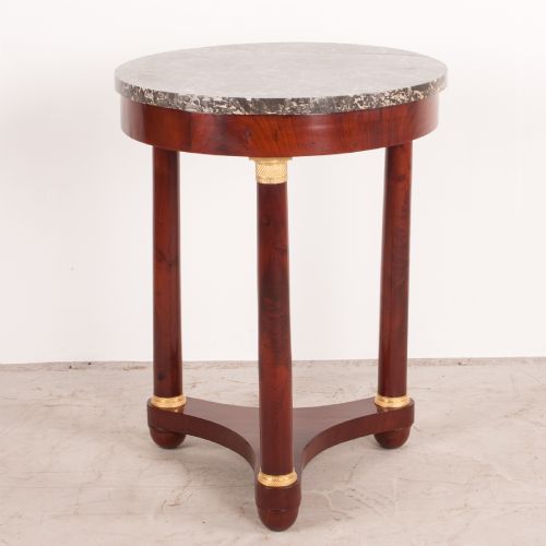 fig 1. A 19th-century French mahogany gueridon side table with a round grey marble top, three cylindrical legs with gilt mounts, and a tri-form concave base.