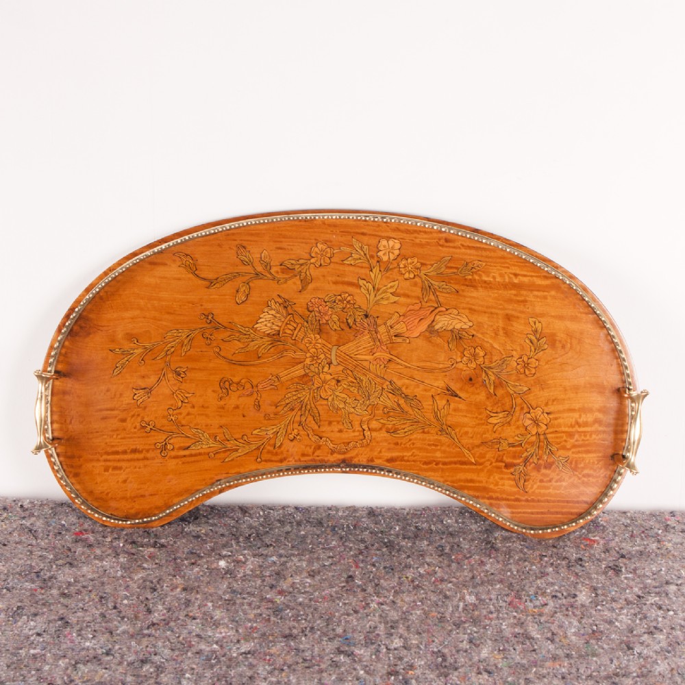 A kidney-shaped satinwood serving tray featuring central floral marquetry inlay, a fitted brass gallery rim, and two side handles.