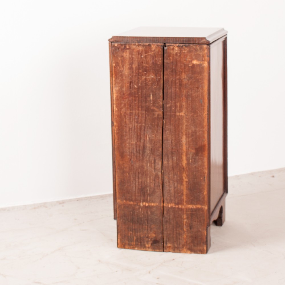 A narrow dark brown mahogany chest featuring four stacked drawers with polished brass drop handles and a shaped bracket foot apron. View IX