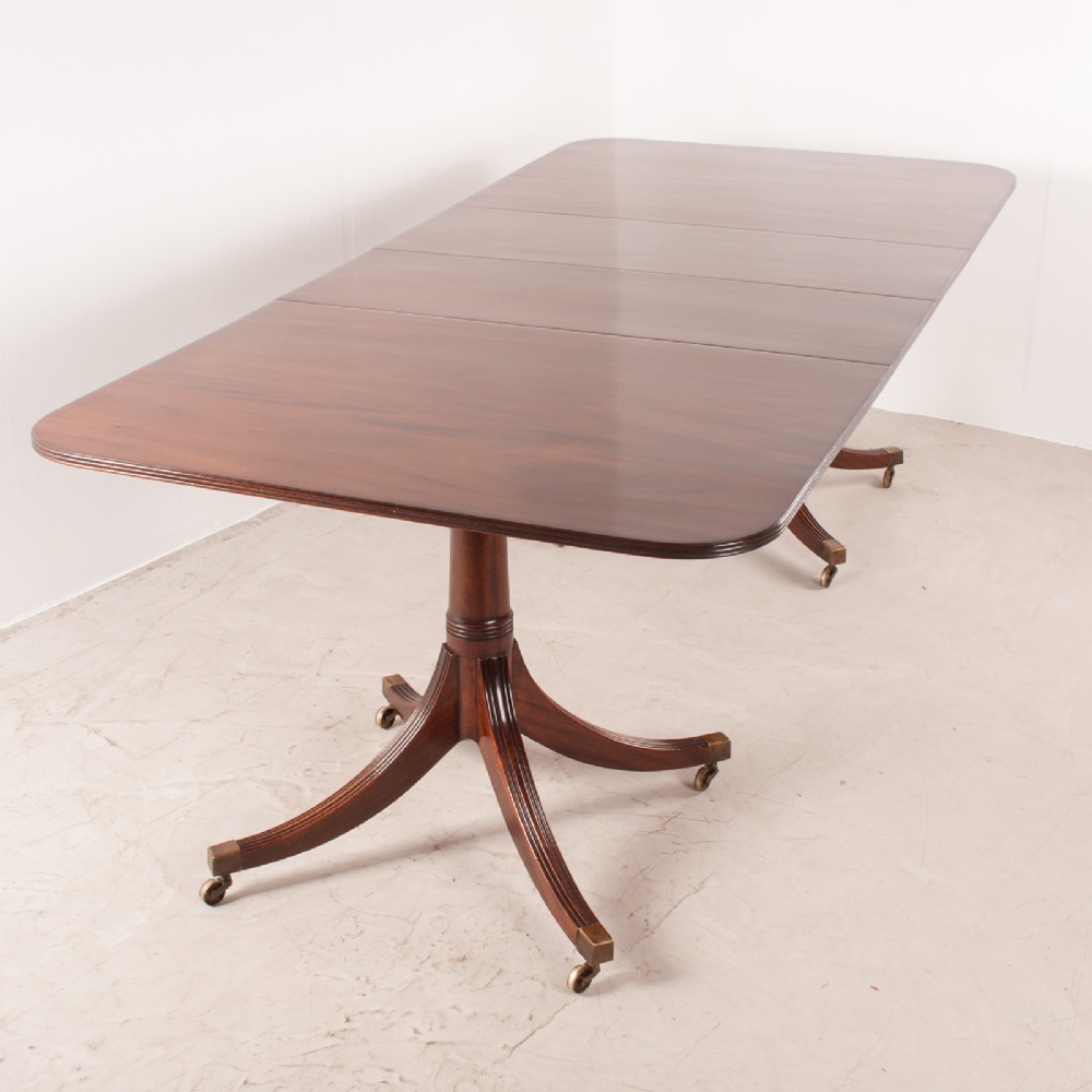 A mahogany twin pillar extending dining table featuring rounded table corners, reeded sabre legs, and brass castors. View II