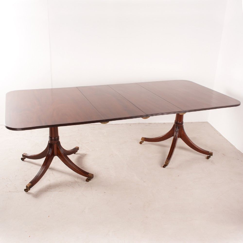 A mahogany twin pillar extending dining table featuring rounded table corners, reeded sabre legs, and brass castors. View V