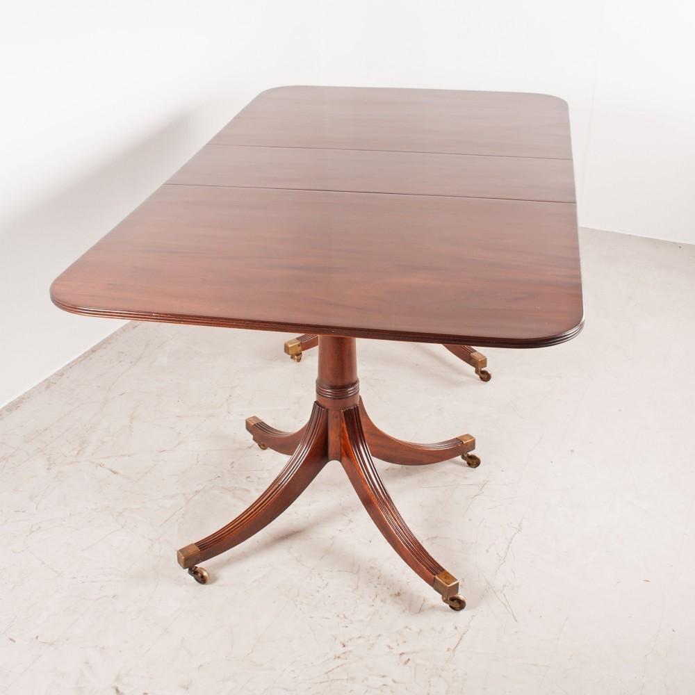 A mahogany twin pillar extending dining table featuring rounded table corners, reeded sabre legs, and brass castors. View VI